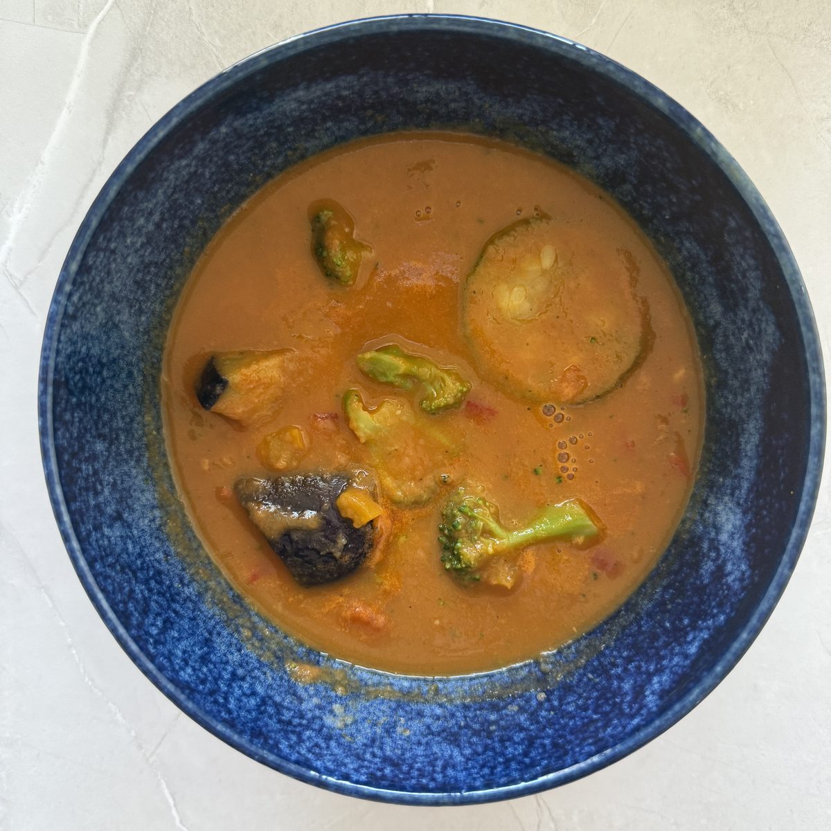 GREEN SPOONのスープ King's Brunch（温野菜たっぷり濃厚トマトのビスクポタージュ）。ズッキーニ・きのこ・ブロッコリーが入ったオレンジ色のポタージュ
